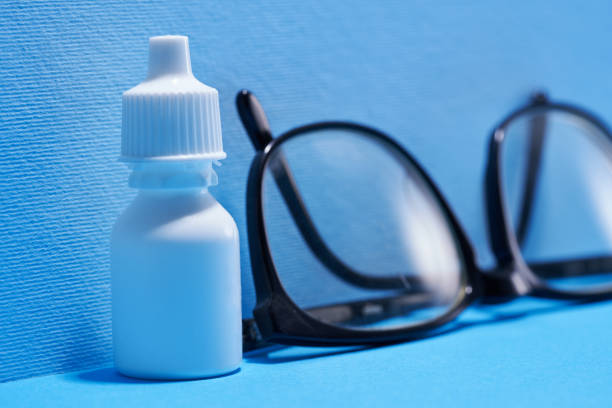 eyedrops and eye glasses against blue background eyedrops and eye glasses against blue background eyedropper stock pictures, royalty-free photos & images