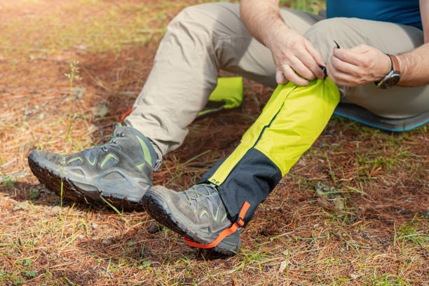 Hiker wears gaiters over trekking boots to protect against water, insects and cold. Clothing and equipment for backpacking and camping stock photo
