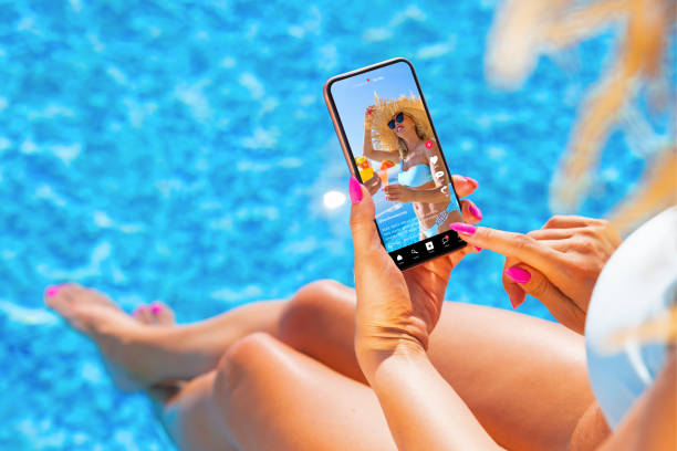 istock Woman using video sharing social media app on phone while sitting by the pool 1385630114