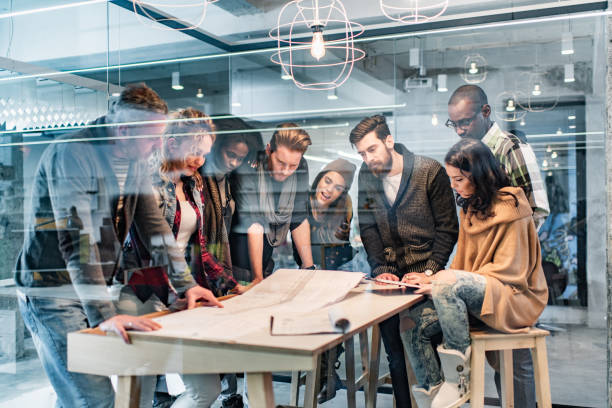 istock Group of building contractors examining blueprints in the office. 1385633559