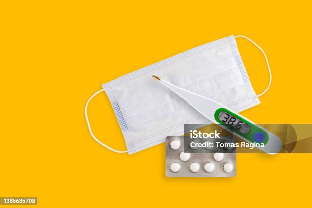 Covid 211218 1face Masks Thermometer And Pills Isolated On A Yellow Background Covid 19 Alpha Beta Gamma Delta Lambda Mu Omicron Variants Outbreak Around The World Stock Photo - Download Image Now