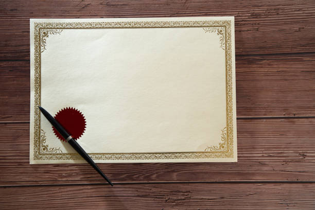 blank certificate and ball pen on wooden table