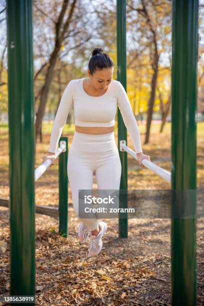Asian Woman In Casual Sports Clothes Working Out On Parallel Bars In The Park Stock Photo - Download Image Now