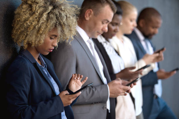 istock People using their phones whilst waiting outside 1385642158