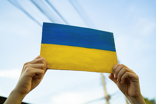 Un hombre sosteniendo cartón pintado en la bandera de Ucrania photo