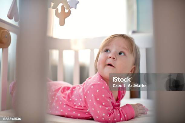 Foto de Menina Feliz Fofa Em Bodysuit Rosa Olhando Para Seu Celular Pendurado Dentro De Casa Em Uma Manhã Ensolarada e mais fotos de stock de Bebê