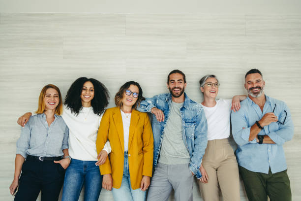 des hommes d’affaires heureux debout contre un mur dans un bureau - cheerful happiness men women photos et images de collection