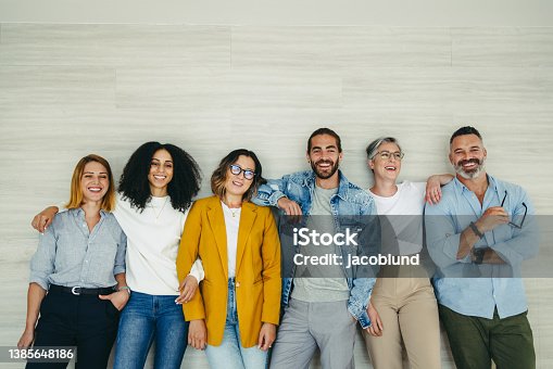 istock Happy businesspeople standing against a wall in an office 1385648186