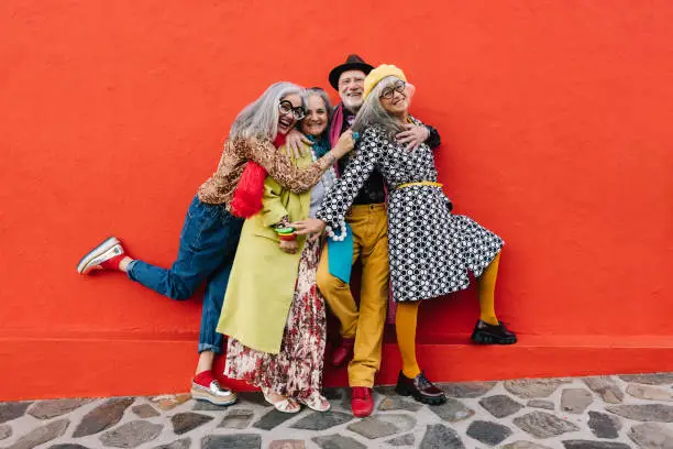 Photo of Group of eccentric senior citizens having fun against a red background