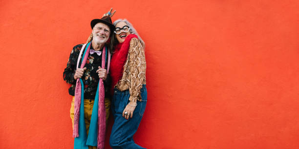 istock Elderly couple laughing happily against a red wall 1385648469