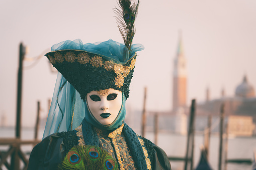 Venetian carnival mask on the white marble background. Full-head black characteristic mask with golden decoration. Flat lay. Copy space for a free text