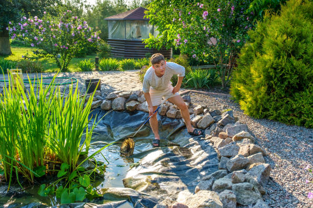 istock Teenager cleaning pond with landing net 1385657501