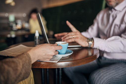 Mature woman talking to a mature businessman in cafe, she is on a job interview.