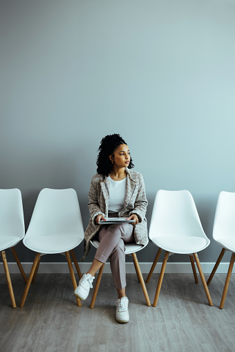 Shot of a young businesswoman sitting in chair in office waiting area