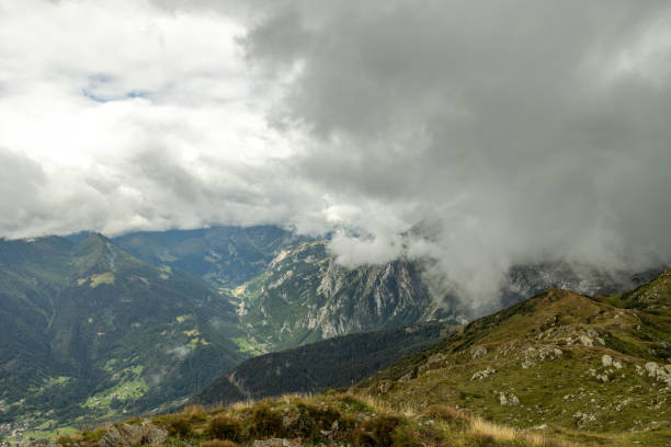 close up view on a beautiful, bright and colorful majestic mountain landscape in the morning during autumn season with variable weather and the sky filled with cumulus clouds, view extending over the mountains up to the horizon, mount Dimon, Ligosullo, Friuli Venezia Giulia, Italy vista de cerca de un hermoso, brillante y colorido paisaje montañoso majestuoso por la mañana durante la temporada de otoño con clima variable y el cielo lleno de nubes cúmulos, vista que se extiende sobre las montañas hasta el horizonte