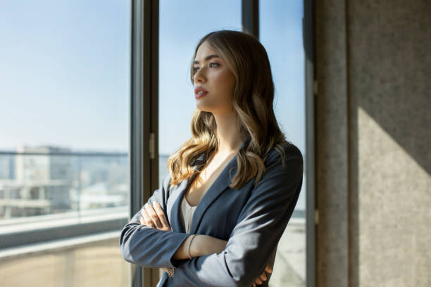 istock Businesswoman wearing suit thinking and looking outdoors through a window at office 1385663121