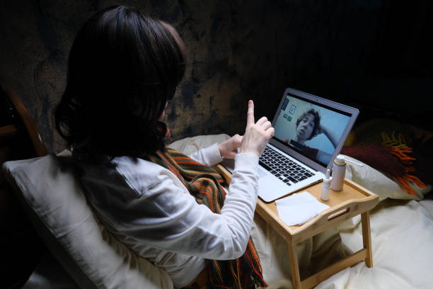 istock Woman is videocalling her friend while staying in bed with flu 1385664861