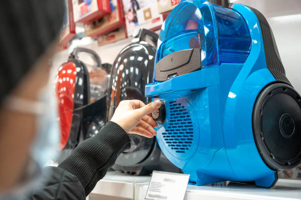 choosing a vacuum cleaner in a home appliance store, a woman's hand checks the vacuum cleaner stock photo