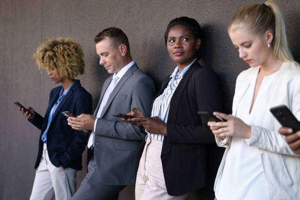 istock People using their phones whilst waiting outside 1385665293