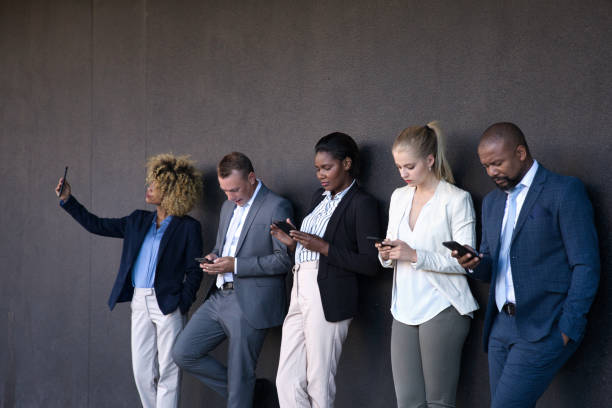 istock People using their phones whilst waiting outside 1385665301