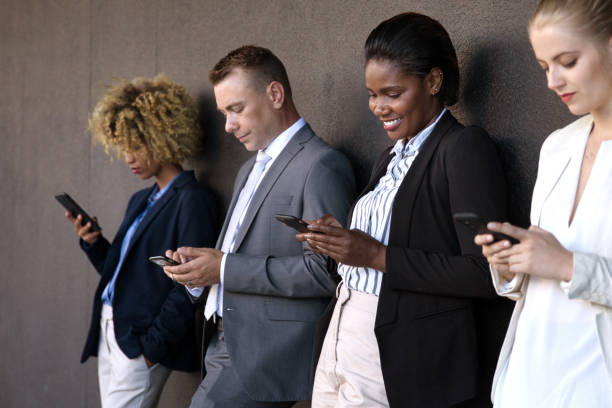 istock People using their phones whilst waiting outside 1385665818