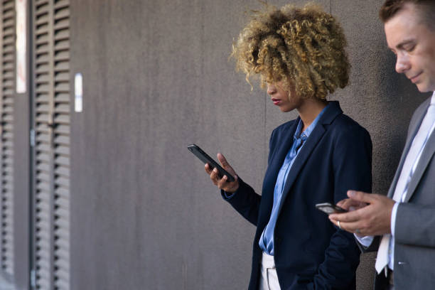 istock People using their phones whilst waiting outside 1385665820