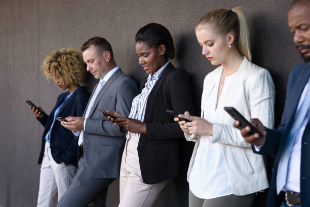 istock People using their phones whilst waiting outside 1385665829