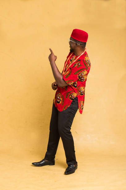 igbo traditionally dressed business man standing point at imaginary product - nigeria african culture dress smiling imagens e fotografias de stock