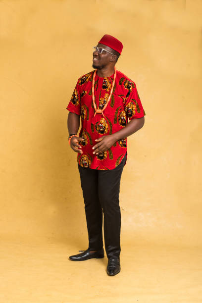 イボ伝統的に服を着たビジネスマンが横を向いて立っている - nigeria african culture dress smiling ストックフォトと画像