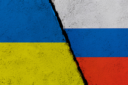 Russian and Ukrainian flags on broken cracked wall.