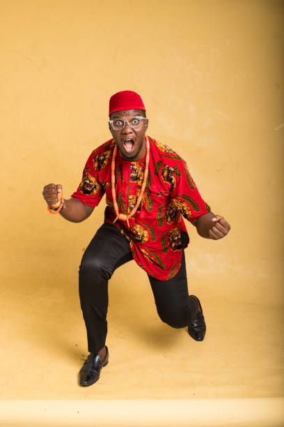 igbo homme d’affaires traditionnellement vêtu de lunettes position gagnante - nigeria african culture dress smiling photos et images de collection