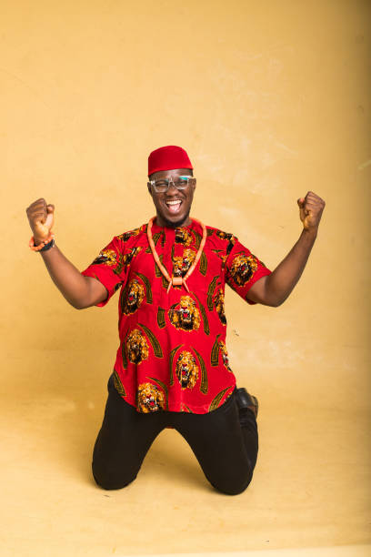 igbo homme d’affaires vêtu traditionnellement gagnant et célébrant - nigeria african culture dress smiling photos et images de collection