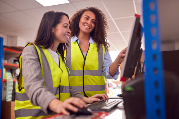 istock Female Staff In Busy Modern Warehouse Working On Computer Terminals 1385667483