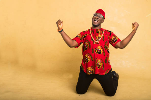 igbo homem de negócios tradicionalmente vestido celebra ajoelhar-se - indigenous culture nigerian culture african descent nigeria - fotografias e filmes do acervo