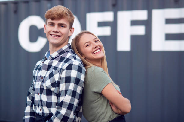 Portrait Of Male And Female Interns At Freight Haulage Business Standing By Shipping Container stock photo