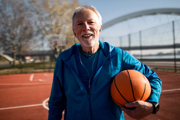 istock Smiling senior taking a break on a basketball court posing looking at camera 1385668162