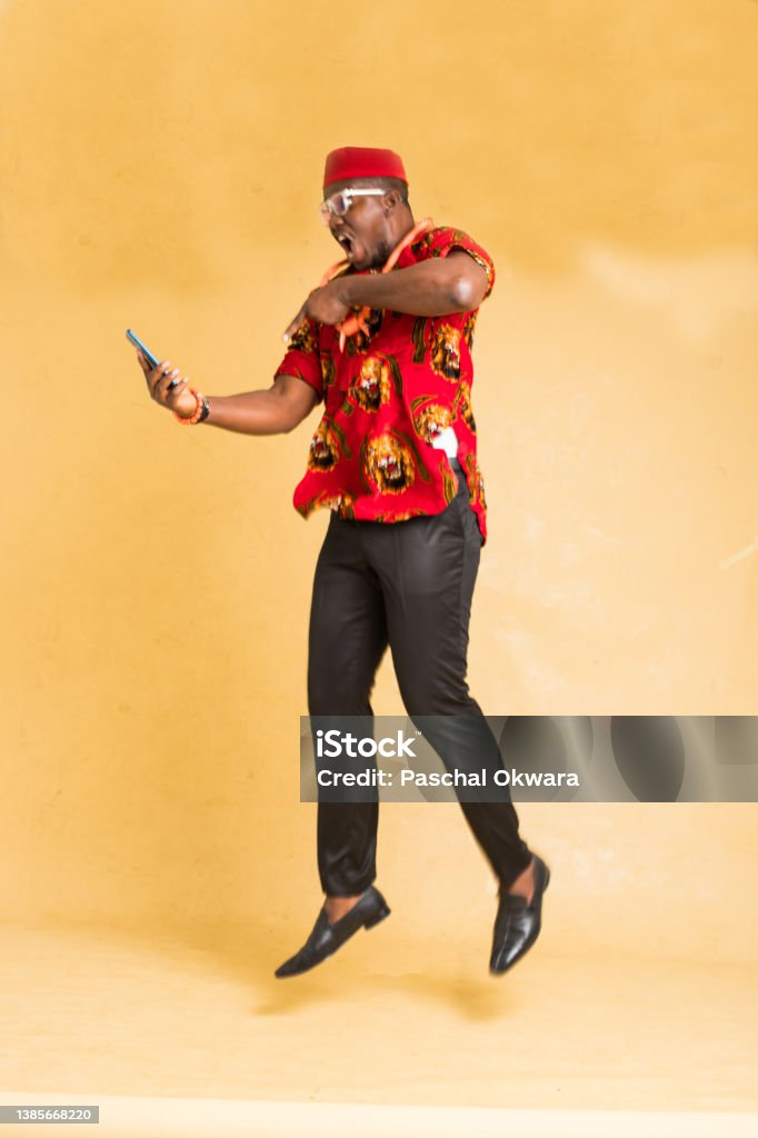 Igbo Traditionally Dressed Business Man in Mid Air with Phone in Hand Igbo People Stock Photo