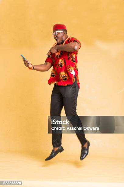 Igbo Traditionally Dressed Business Man In Mid Air With Phone In Hand Stock Photo - Download Image Now