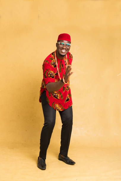 igbo homme d’affaires habillé traditionnellement debout dansant avec la main en avant - nigeria african culture dress smiling photos et images de collection