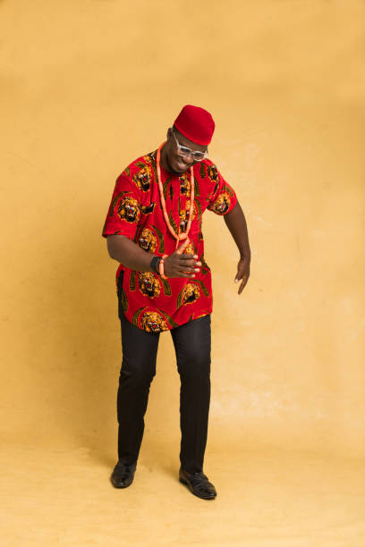 igbo traditionally dressed business man standing dancing - nigeria african culture dress smiling imagens e fotografias de stock