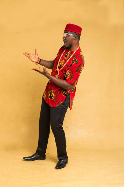 istock Igbo Traditionally Dressed Business Man Standing Highlighting a Product with Both Hands 1385668444