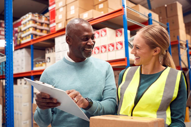istock Male Team Leader With Clipboard In Warehouse Training Intern Standing By Shelves 1385668575