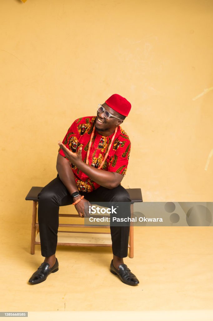 Igbo Traditionally Dressed Business Man Sitting Down Display an Imaginary Product Igbo People Stock Photo