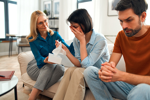 A young married couple came to an appointment and consultation with a psychotherapist. Counseling and help during depression and solving family problems. Woman crying at the psychologist.