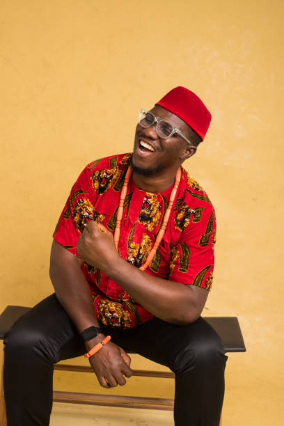 igbo traditionally dressed business man sitting down and laughing - nigeria african culture dress smiling imagens e fotografias de stock