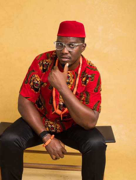 igbo traditionally dressed business man sitting down and looking handsome - nigeria african culture dress smiling imagens e fotografias de stock