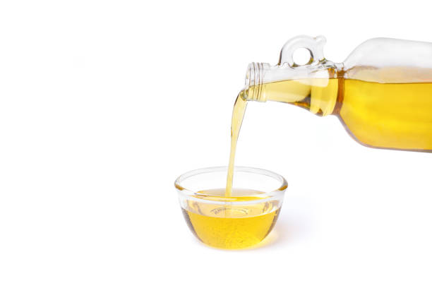 Cooking oil or olive oil pouring from glass bottle into glass bowl isolated on white Cooking oil pouring from glass bottle into glass bowl isolated on white background. olive oil pouring antioxidant liquid stock pictures, royalty-free photos & images