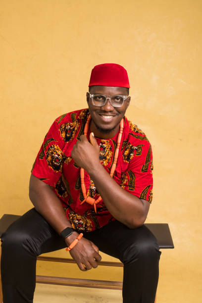 igbo tradicionalmente vestido homem de negócios sentado e sorrindo - indigenous culture nigerian culture african descent nigeria - fotografias e filmes do acervo