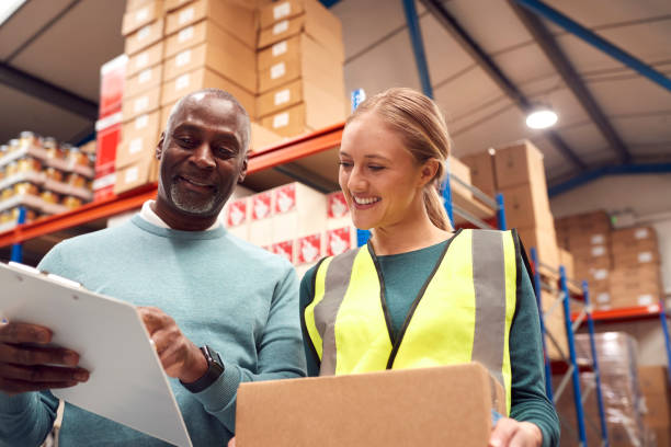 istock Male Team Leader With Clipboard In Warehouse Training Intern Standing By Shelves 1385669401