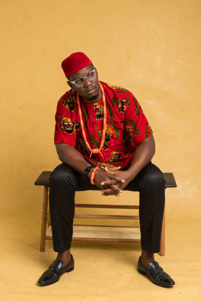 igbo traditionally dressed business man sitting down and stare away - nigeria african culture dress smiling imagens e fotografias de stock